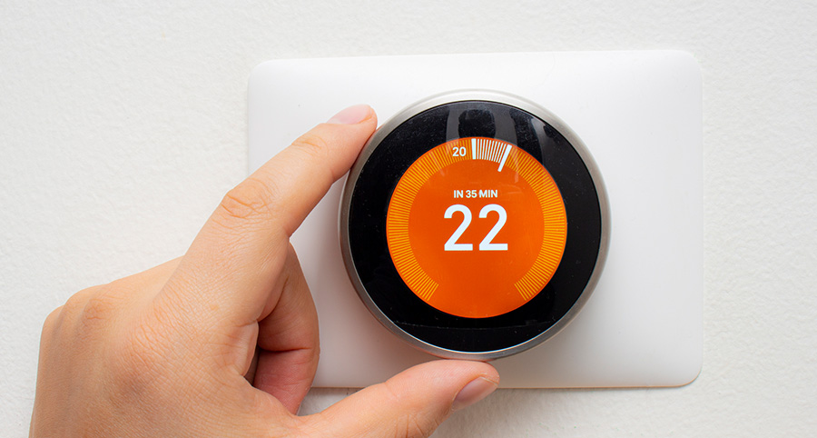 close up with a smart thermostat with an orange background